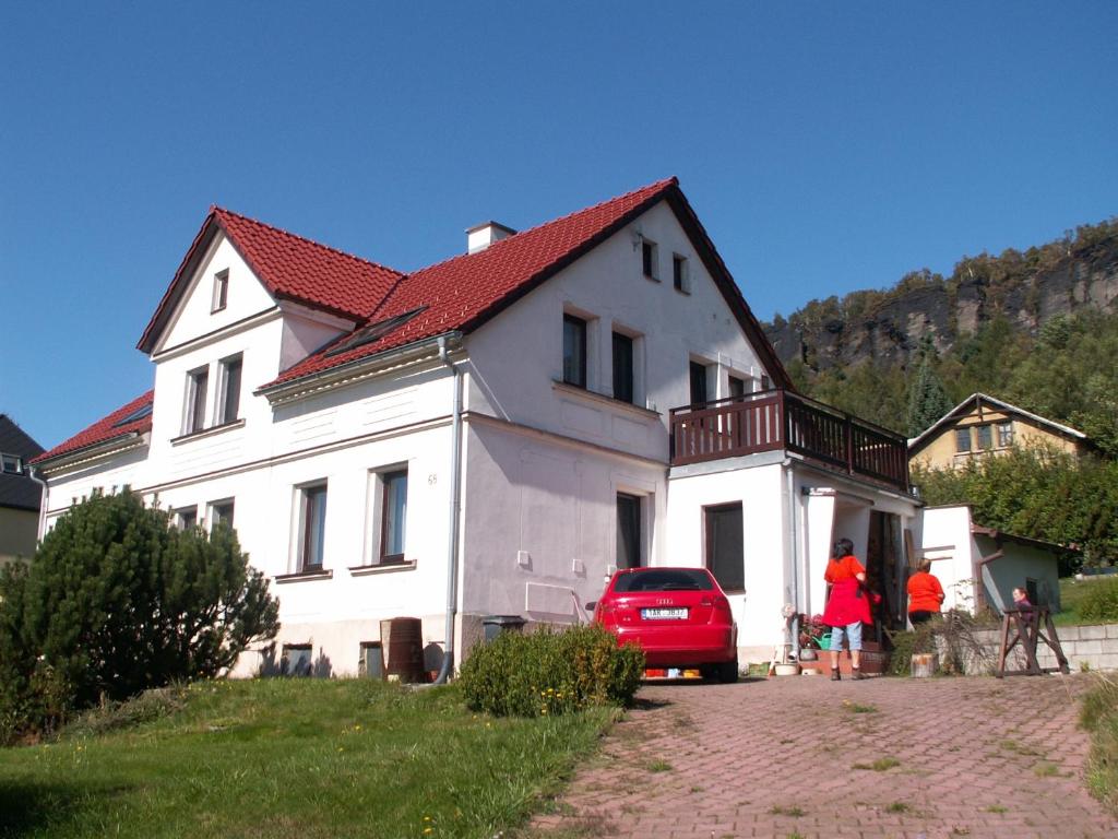 Biały dom z czerwonym dachem i czerwonym samochodem w obiekcie Apartmán Tisá 68 w mieście Tisá