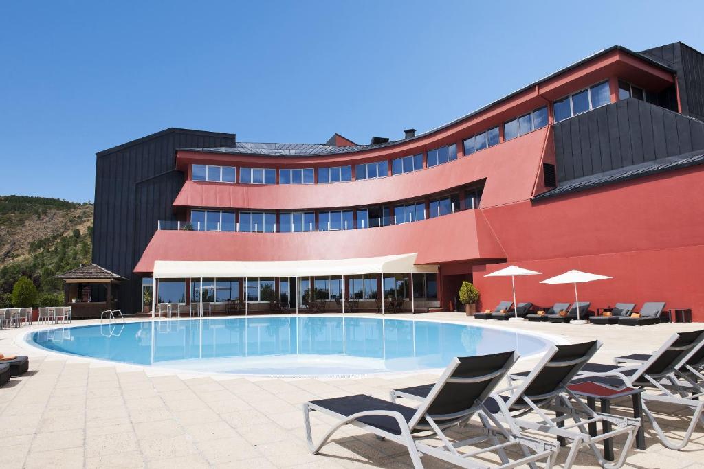 um hotel com piscina em frente a um edifcio em Luna Hotel dos Carqueijais - Serra da Estrela na Covilh