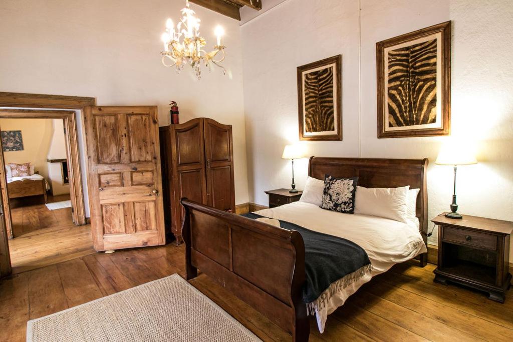1 dormitorio con cama y lámpara de araña en Garden House en Graaff-Reinet