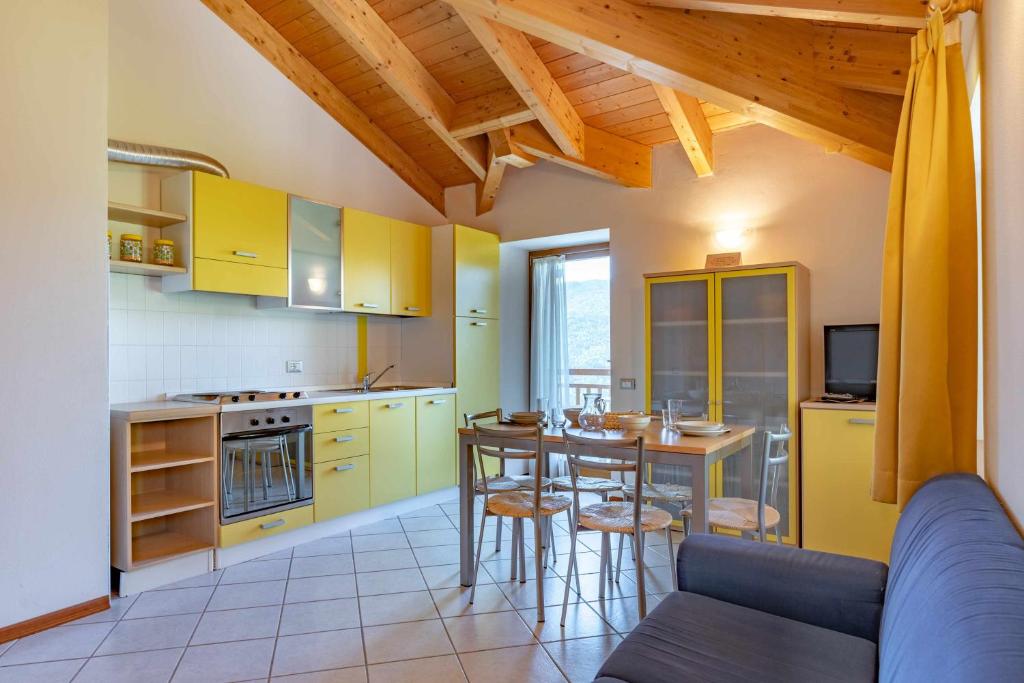 una cucina con armadi gialli e tavolo con sedie di Appartamento al Sol Grauno Ospitar a Grauno