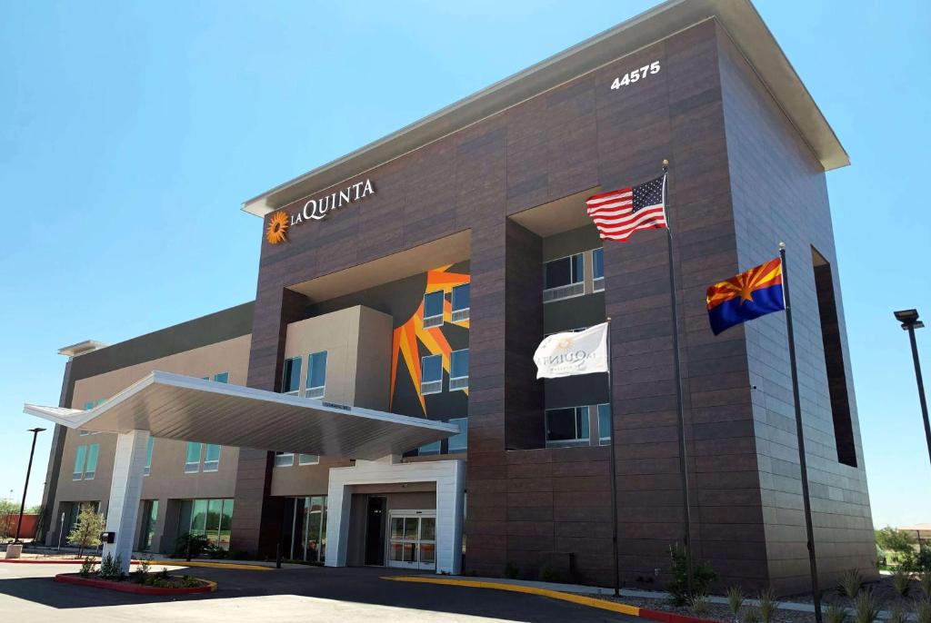 a building with flags in front of it at La Quinta Inn & Suites by Wyndham Maricopa Copper Sky in Maricopa