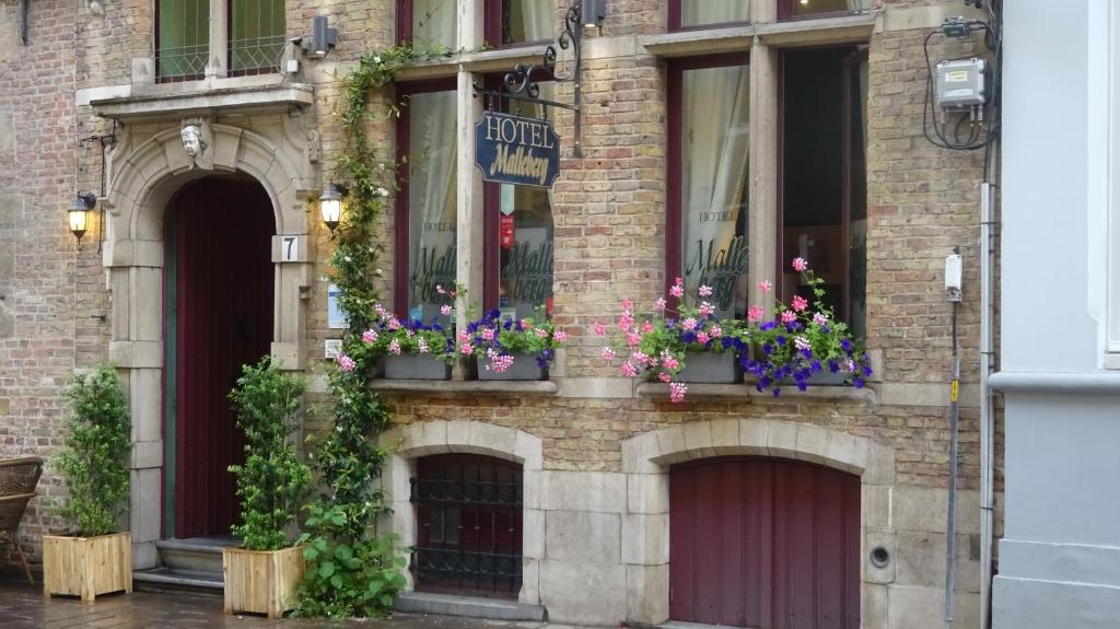a brick building with flowers in window boxes at Hotel Malleberg in Bruges
