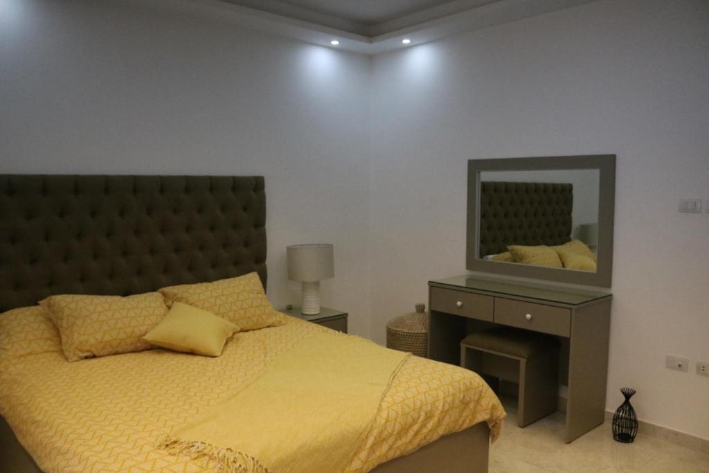 sypialnia z łóżkiem z żółtą kołdrą i lustrem w obiekcie Amazing one Bedroom Apartment in Amman Elwebdah 8 w mieście Amman