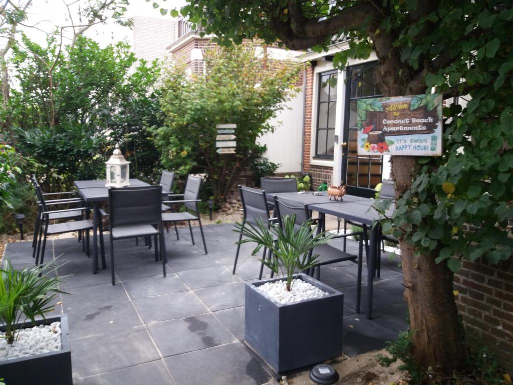 Un patio con mesas y sillas y un árbol. en Coconut Beach apartments, en Zandvoort
