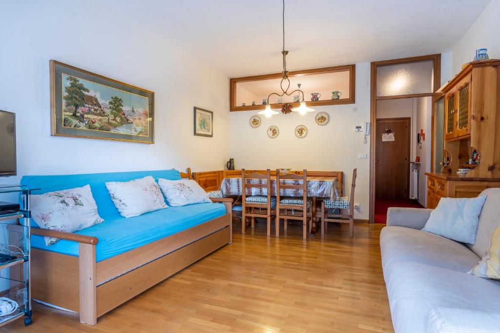 a living room with a blue couch and a dining room at Il Ruscello Apartment with Terrace and View of the Alps in Tarvisio