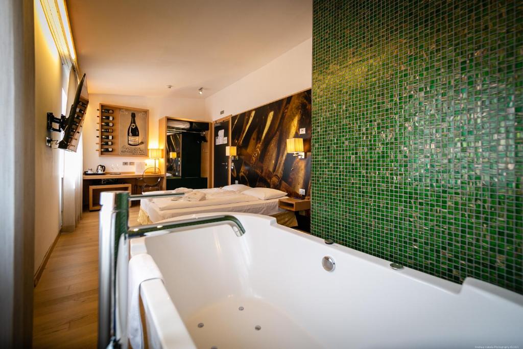 a bathroom with a tub and a green tile wall at Boutique Exclusive B&B in Trento
