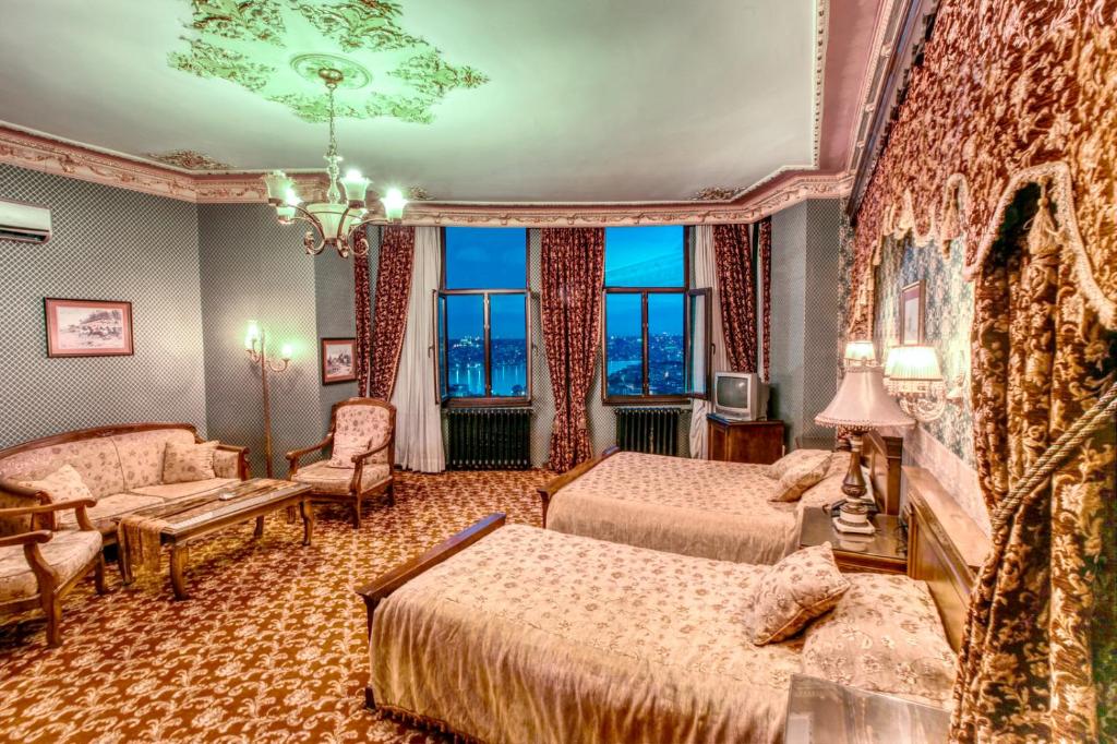 イスタンブールにあるGrand Hotel de Londresのベッド2台とソファが備わるホテルルームです。