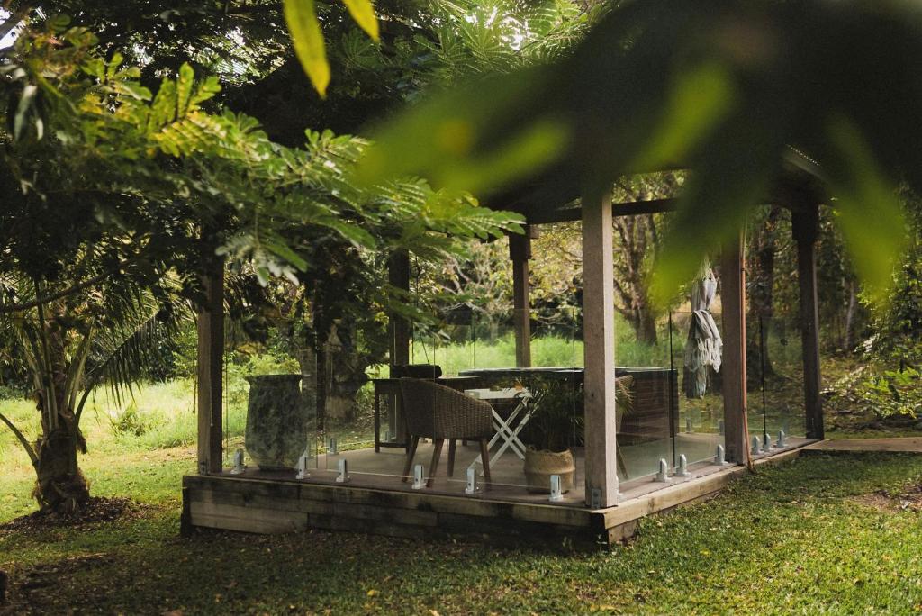 einen hölzernen Pavillon mit einem Tisch und einem Stuhl in der Unterkunft Palm Grove Rainforest Retreat in Palm Grove