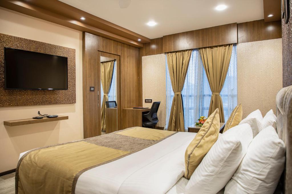 um quarto de hotel com uma cama e uma televisão de ecrã plano em Hotel Rajmahal em Guwahati