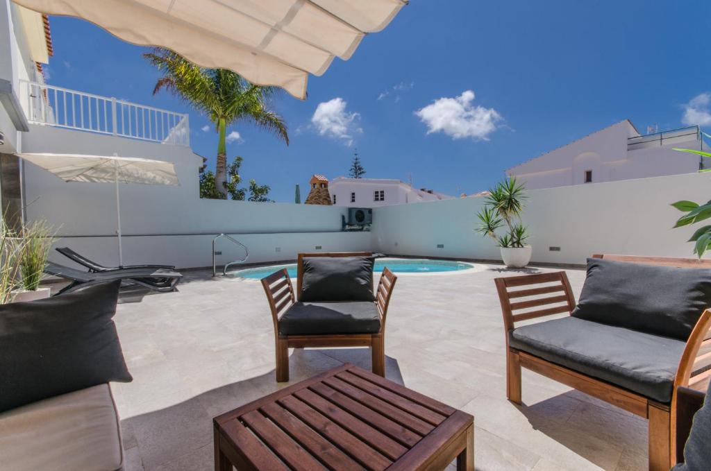 eine Terrasse mit Stühlen und einem Pool in der Unterkunft Vv Sunny Holiday Villa Maspalomas in Maspalomas