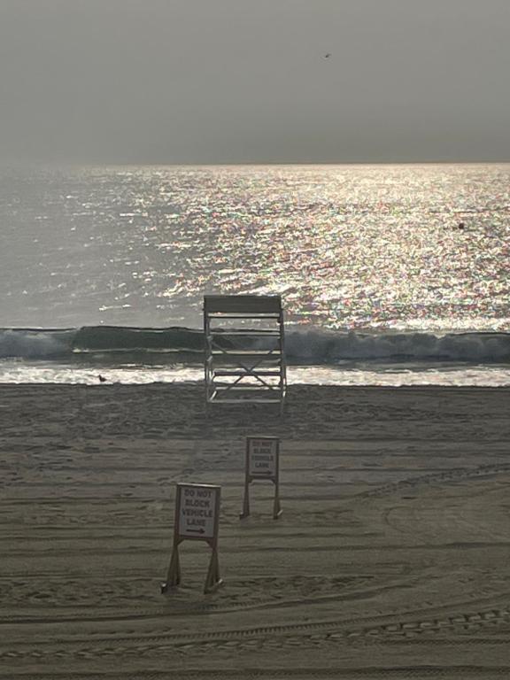 una panchina sulla spiaggia con due cartelli nella sabbia di Room near the Beach and Pier Village a Long Branch