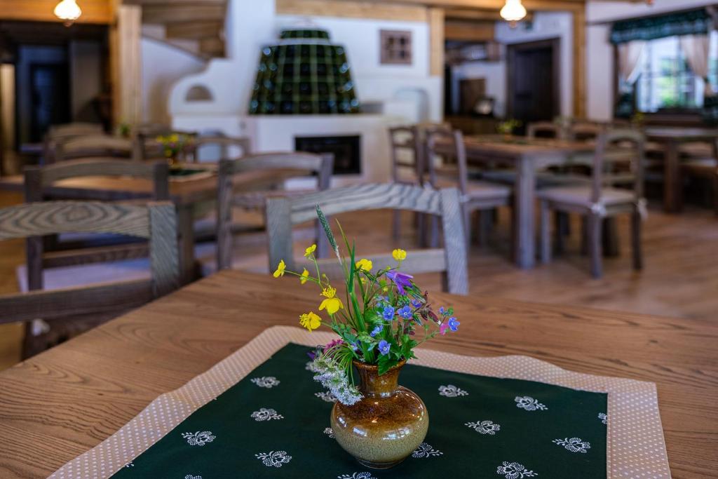 un jarrón con flores en una mesa en un restaurante en Stará Zvonica en Nižná Boca