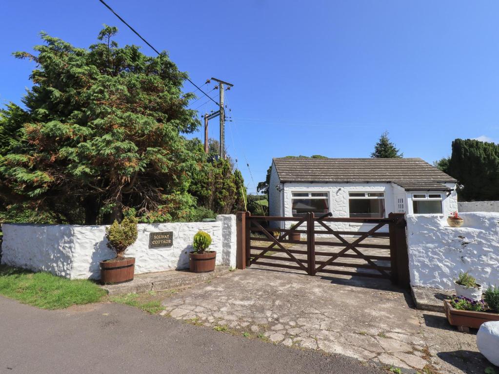 una casa blanca con una puerta y una valla en Solway Cottage en Annan