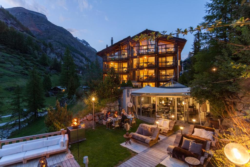 un grand bâtiment avec des personnes assises sur une terrasse dans l'établissement Suitenhotel Zurbriggen, à Zermatt