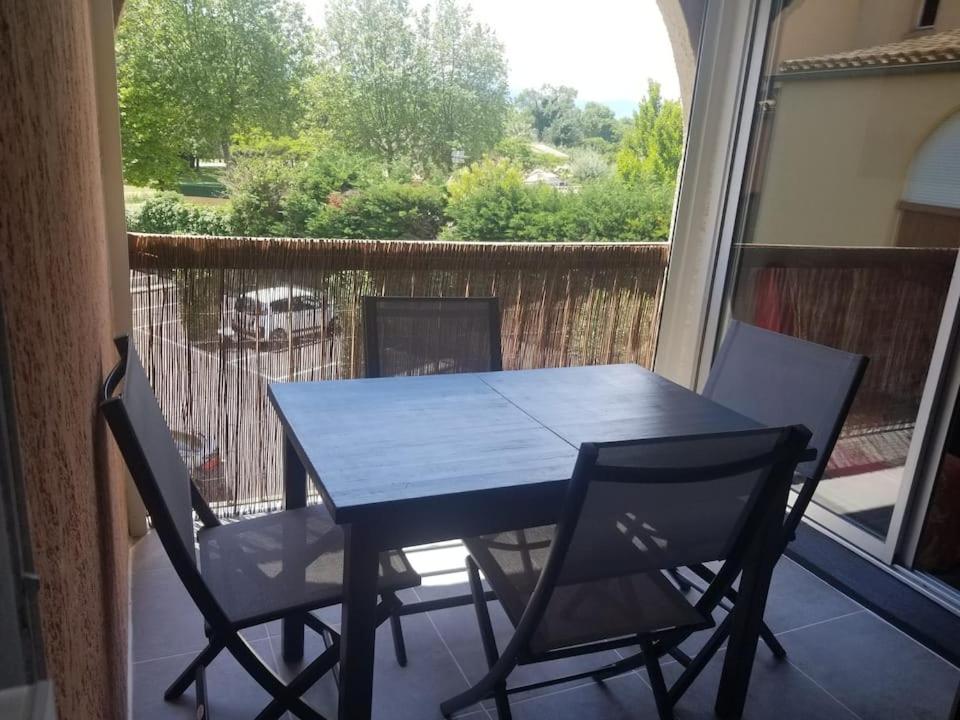 une table bleue et des chaises sur un balcon avec une fenêtre dans l'établissement Appartement dans la verdure près des plages, à Saint Cyprien Plage
