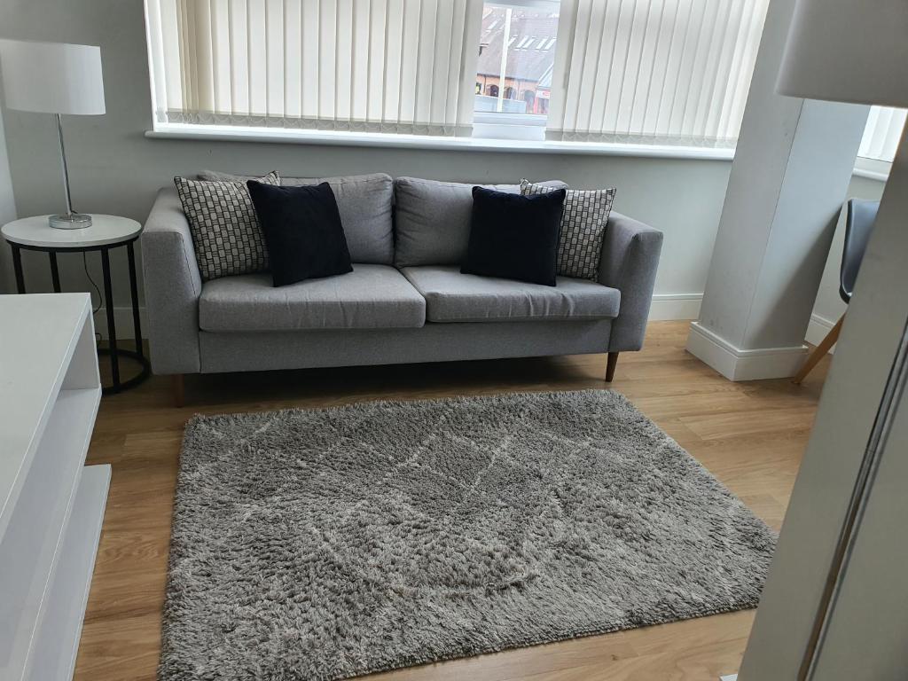 a living room with a grey couch and a rug at Vetrelax Chelmsford Roseberry Apartment in Chelmsford