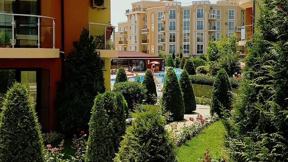 a garden with trees and bushes in front of a building at Ravda Sun Sea Ressort 2 in Ravda