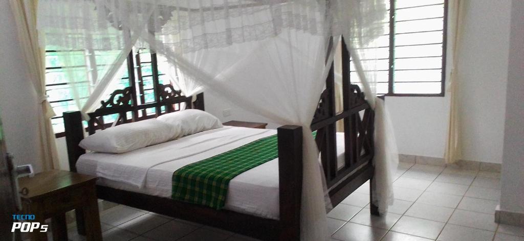 a bedroom with a bed in a room with a window at Diani Horizon Beach Cottages in Diani Beach