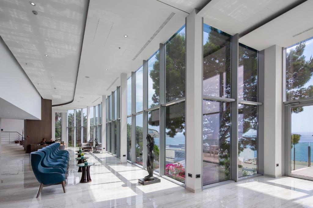 a lobby with a blue chair and large windows at Royal Neptun Hotel in Dubrovnik