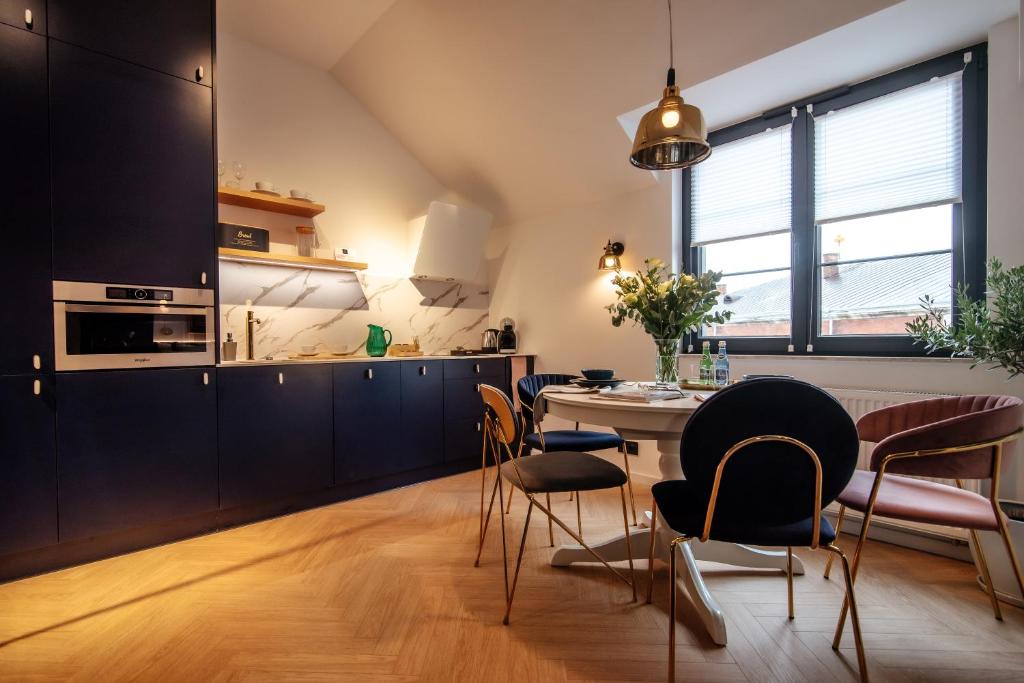 uma cozinha com armários pretos e uma mesa e cadeiras em Apartamenty Stare Miasto Zamość em Zamość