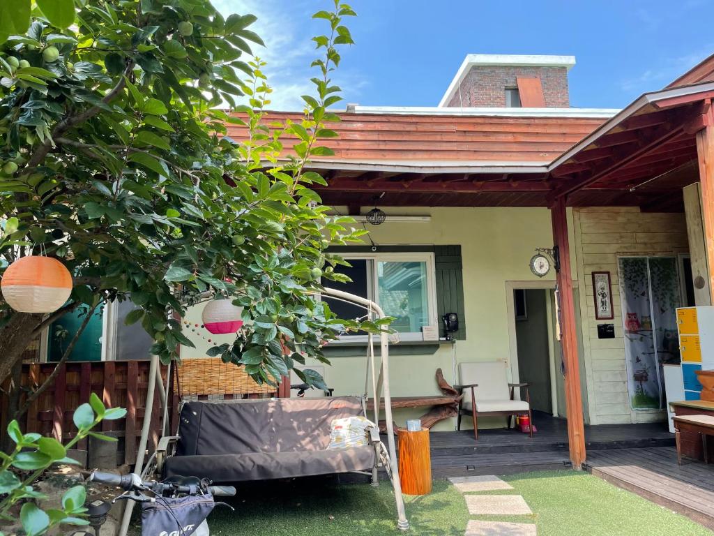 una casa con un porche con un árbol en Gyeongju Momojane Guesthouse, en Gyeongju