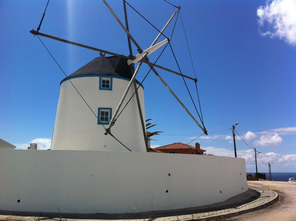 un molino de viento sentado detrás de una pared blanca en Moinho do Roque, en Lourinhã