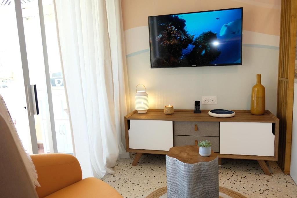 a living room with a television on a wall at Elégant appartement moderne - Cure et vacances in Balaruc-les-Bains