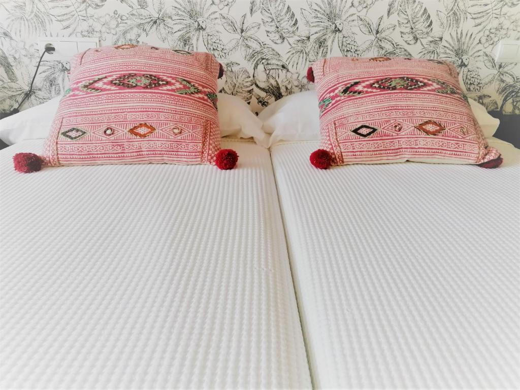 2 camas blancas con almohadas rosas encima en El Sumiciu, en Avilés