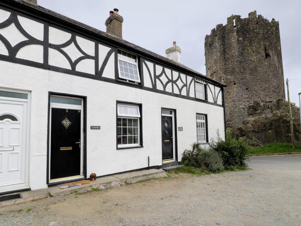 a white and black building with a castle at Y Bwthyn in Conwy