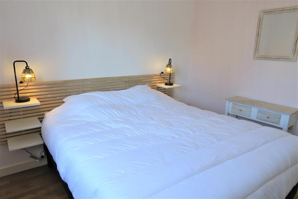 une chambre avec un grand lit blanc avec deux lampes dans l'établissement Maison avec WIFI, jardin, à 900m de la plage de Trestraou à PERROS-GUIREC Ref 849, à Perros-Guirec