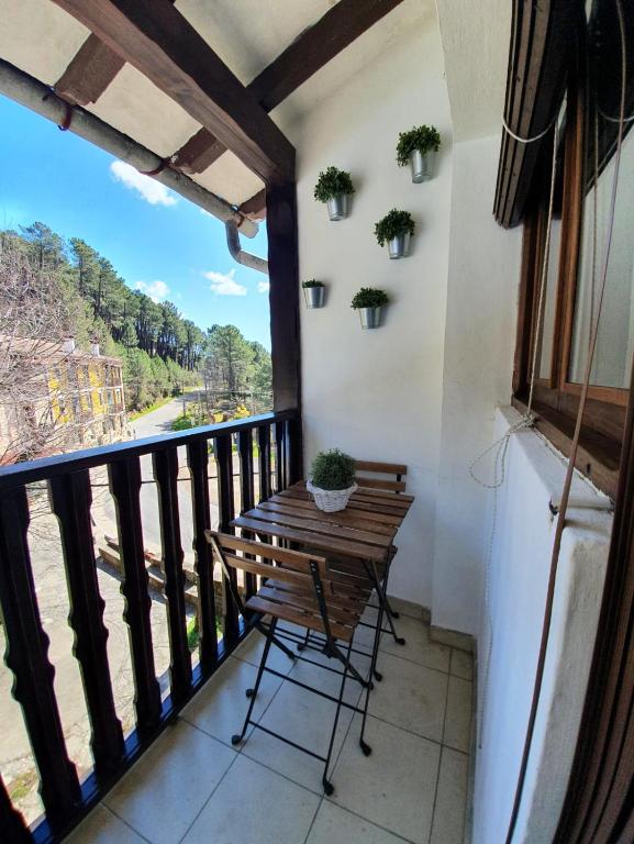 a balcony with a wooden table and a view at La Estrella de Gredos in Guisando