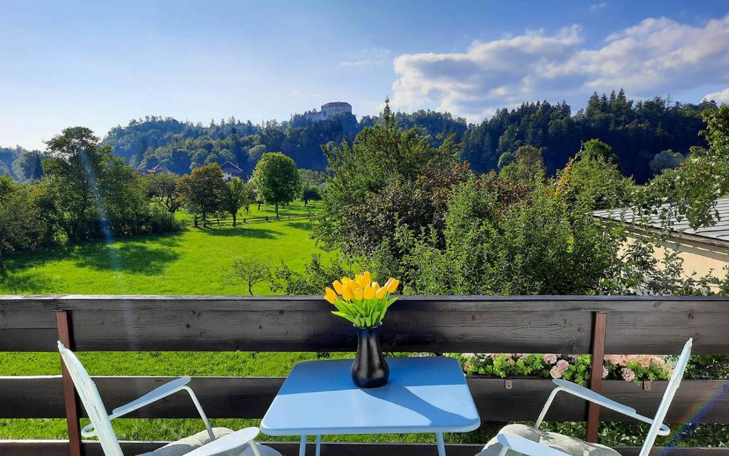 een vaas met bloemen op een tafel met stoelen bij Deerwood Villa-Modern cozy apartment with castle view in Bled