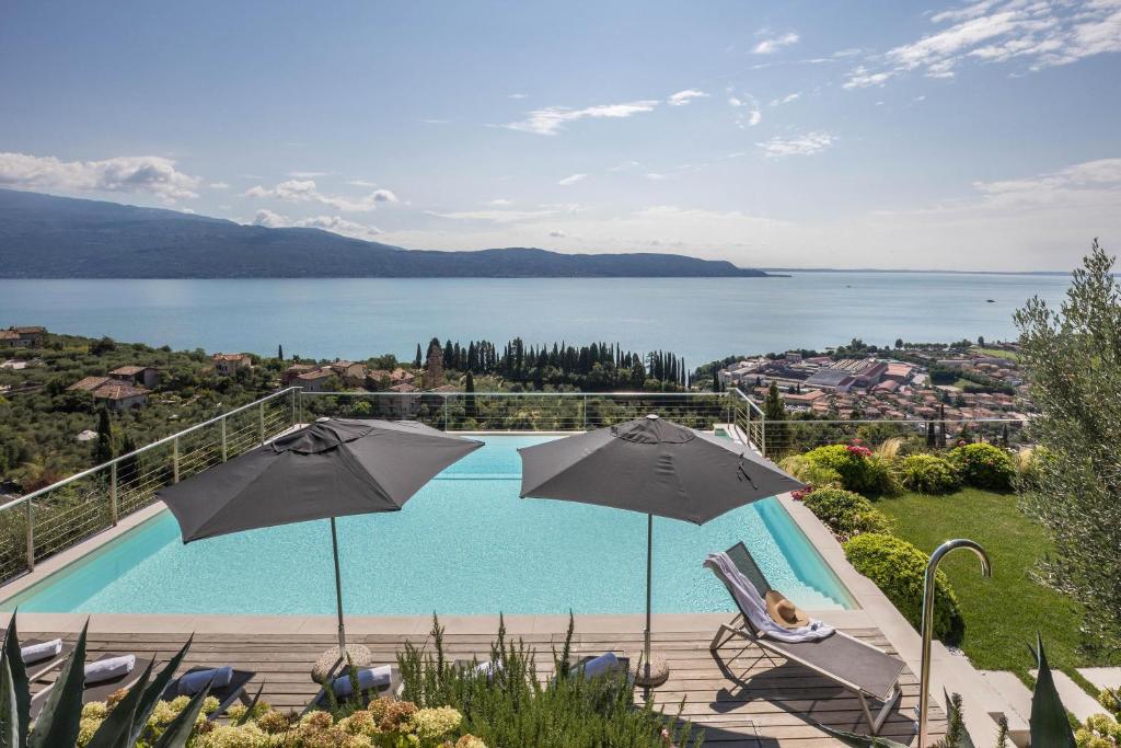 a swimming pool with two umbrellas and a view of the water at Exclusive Villa Agave in Toscolano Maderno