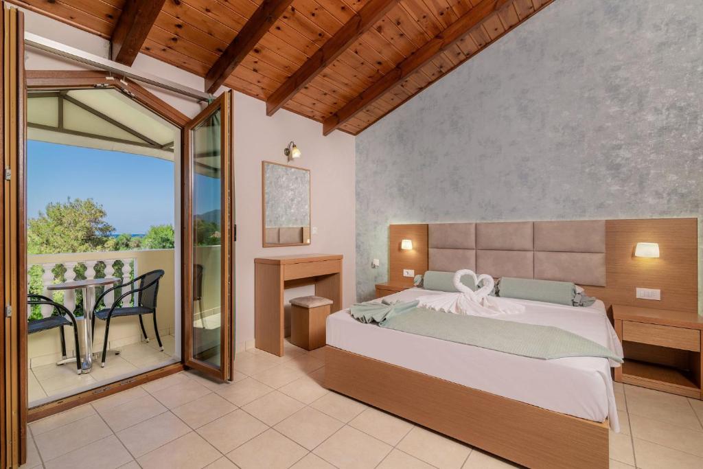 Plaka Beach Resort في فاسيليكوس: غرفة نوم مع سرير وبلكونة مع طاولة
