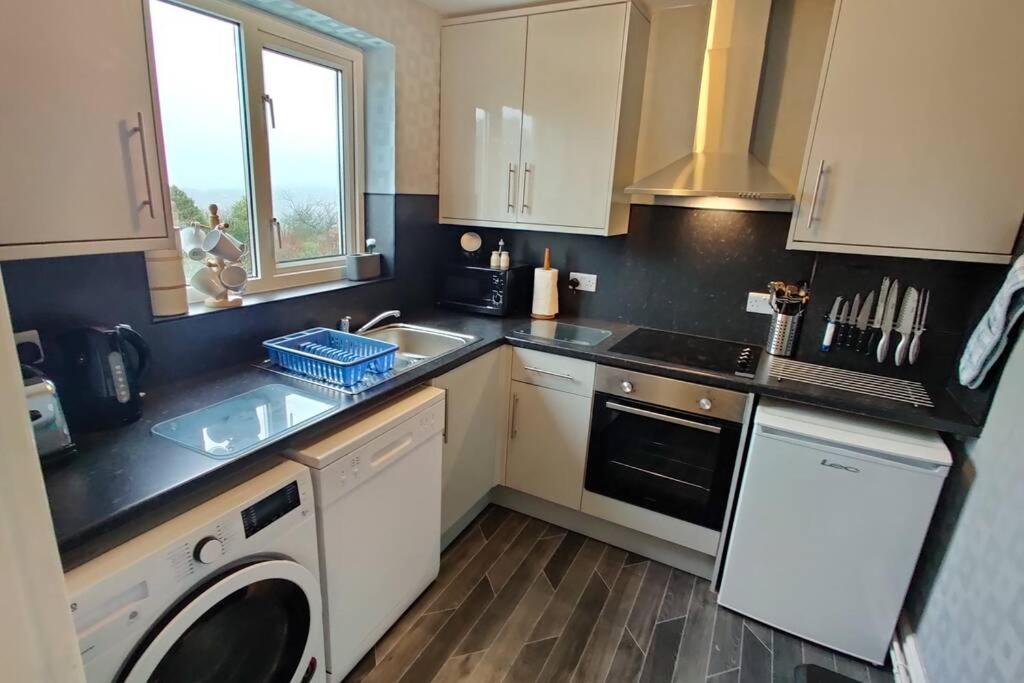 a kitchen with white cabinets and a washer and sink at Glen View a Stones Throw away from The Gower! in Swansea