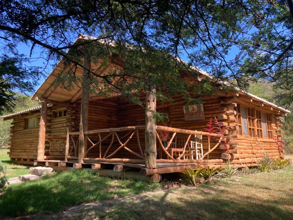 Cabaña de madera con porche y árbol en Inraki Lodge, en Guaillabamba