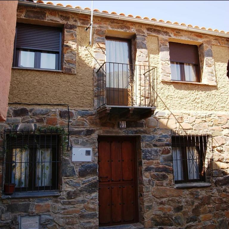 - un bâtiment en pierre avec une porte en bois et un balcon dans l'établissement El Volvedero, à Castillo