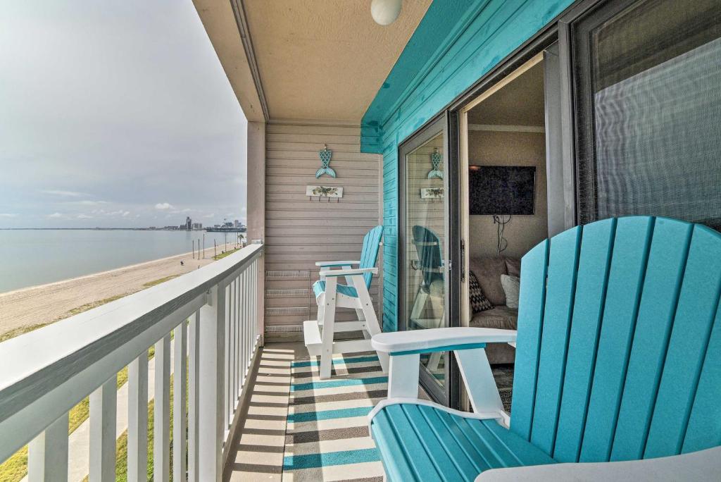 a porch with two blue chairs and the ocean at Updated Front Beach Condo w/ Resort Amenities! in Corpus Christi