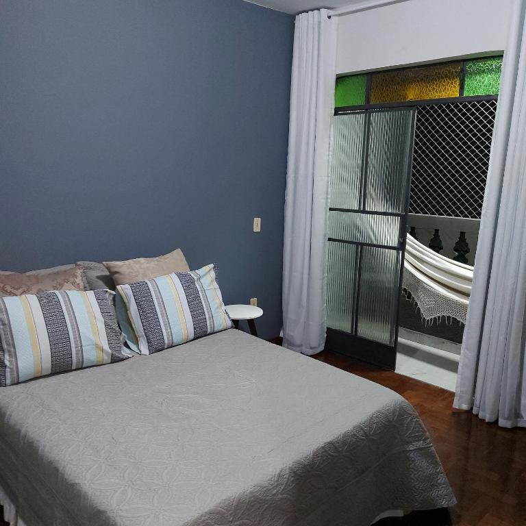 a bedroom with a bed and a window with a balcony at Apartamento Aconchegante in Divinópolis