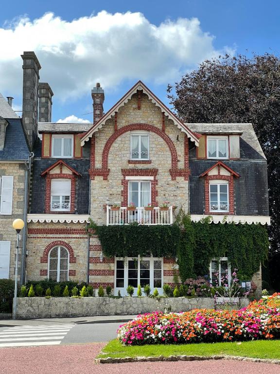ein Backsteinhaus mit Blumen davor in der Unterkunft Le Grand Chalet in Bagnoles de l&#39;Orne
