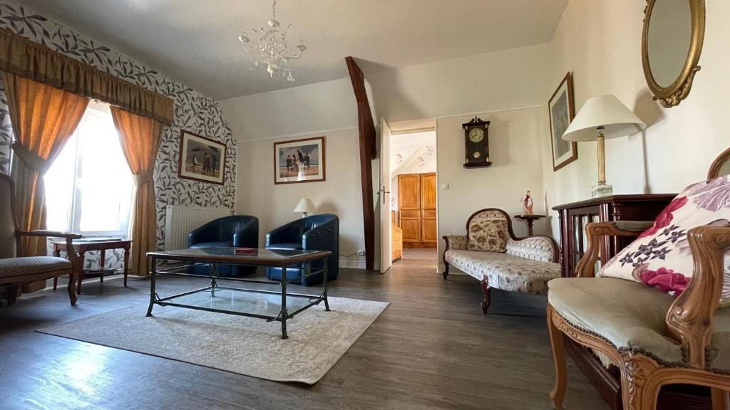 a living room with a couch and chairs and a table at Le Grand Chalet in Bagnoles de l'Orne