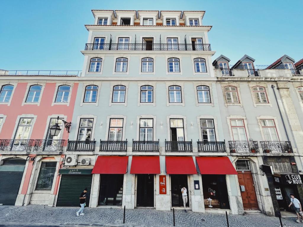 un gran edificio blanco con toldos rojos. en Esqina Cosmopolitan Lodge, en Lisboa