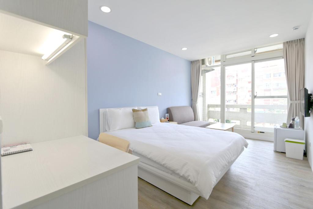 a white bedroom with a bed and a window at Locomotive Homestay in Tamsui