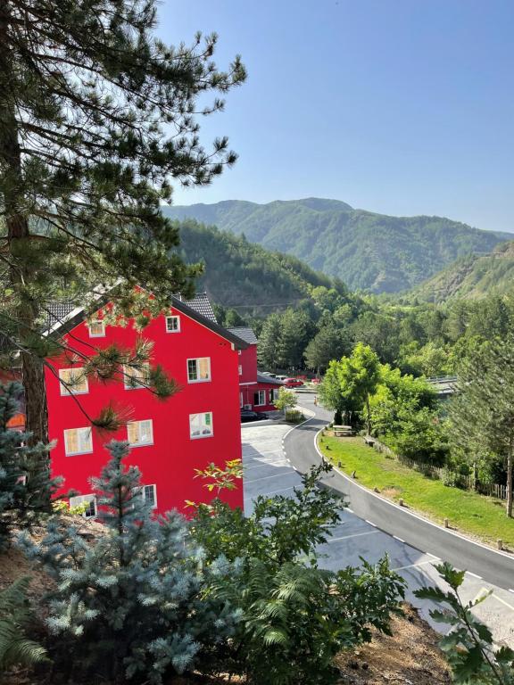 uma casa vermelha na berma de uma estrada em Hotel SH & SH em Pukë