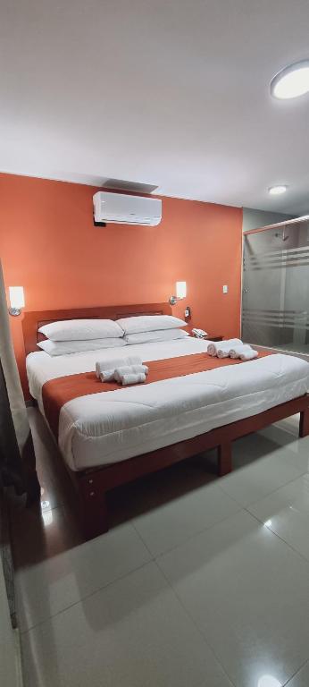 Cama grande en habitación con pared de color naranja en Ensenada Hotel, en San Juan