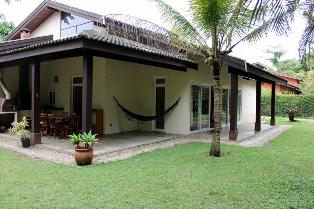 a house with a palm tree in front of it at Praia de Itamambuca- Casa charmosa e iluminada in Ubatuba