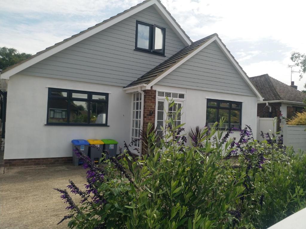 a white house with black windows and purple flowers at Stylish holiday let in central Broadstairs in Broadstairs