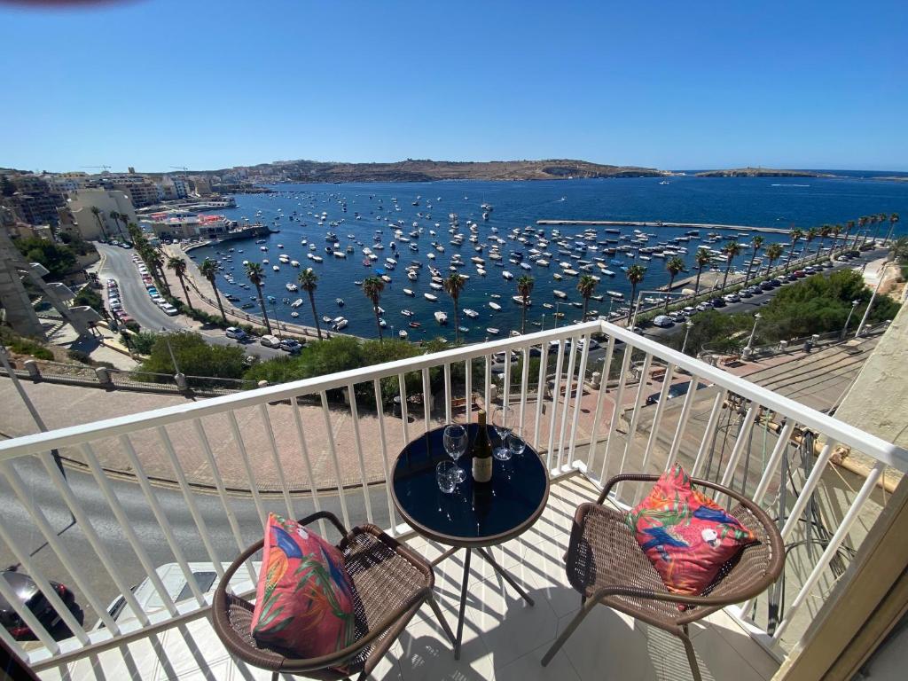 a balcony with a table and chairs with a view of a harbor at St Paul's Bay Sunset View Apartment in St. Paul's Bay