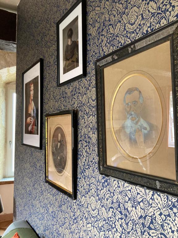 a wall with framed pictures of a man on it at Chambre Loulou • Maison Colombage in Provins
