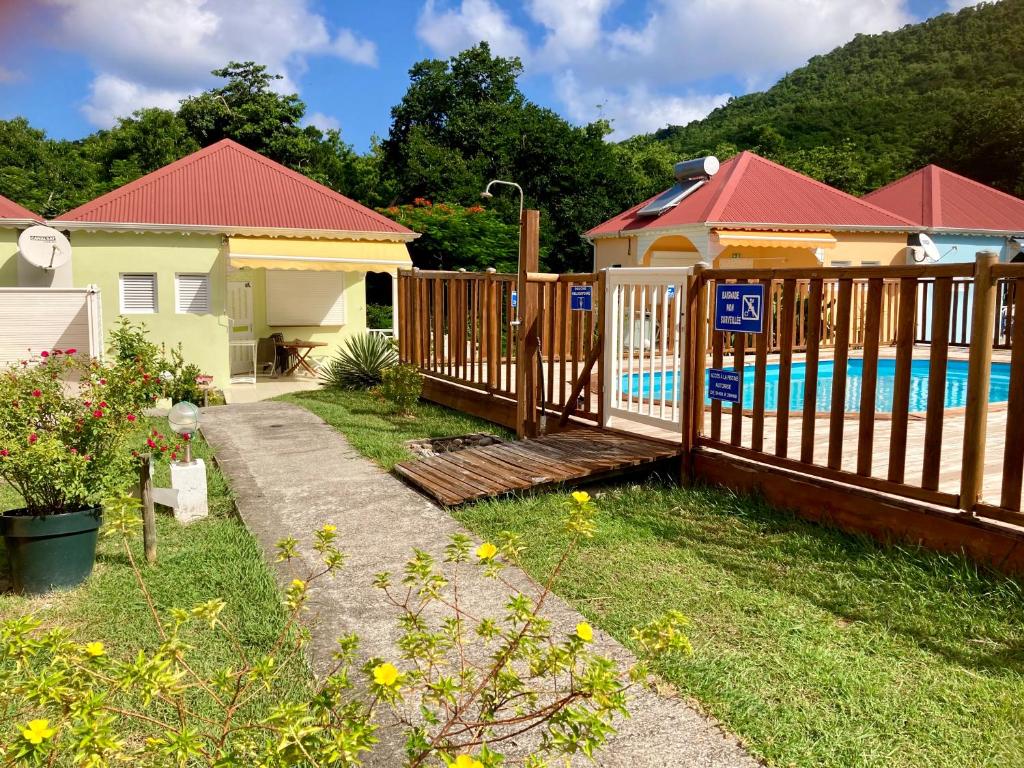 una valla de madera frente a una casa con piscina en Residence Soleil Demery en Terre-de-Bas
